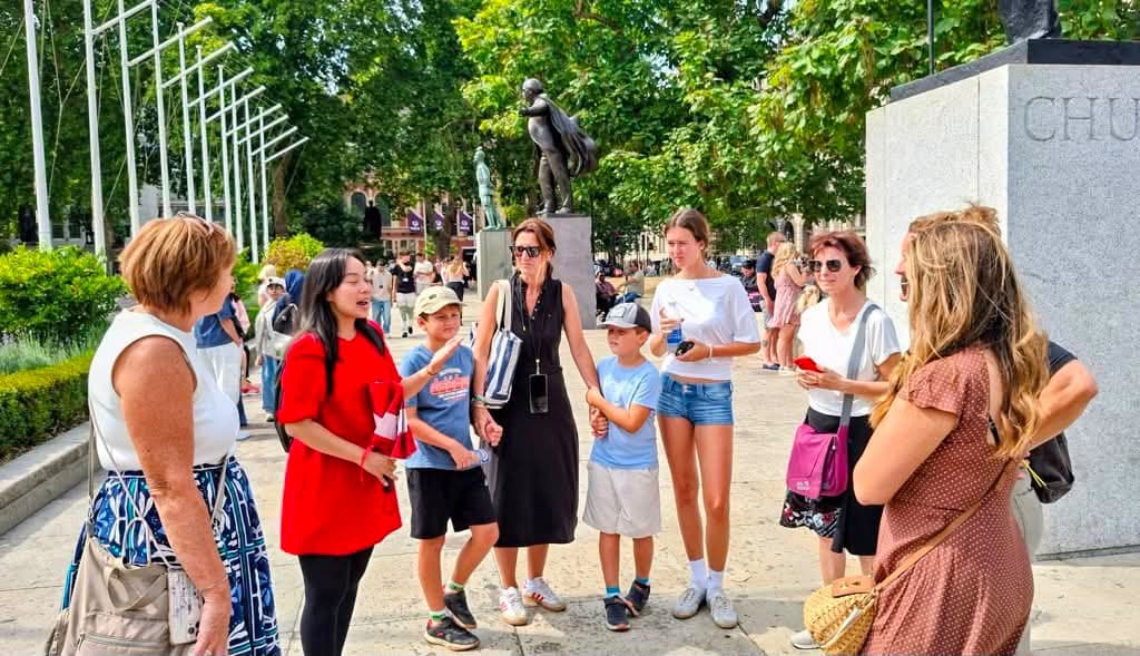 A BeExplorers guide talking to a family group beside the Churchill statue in Parliament Square